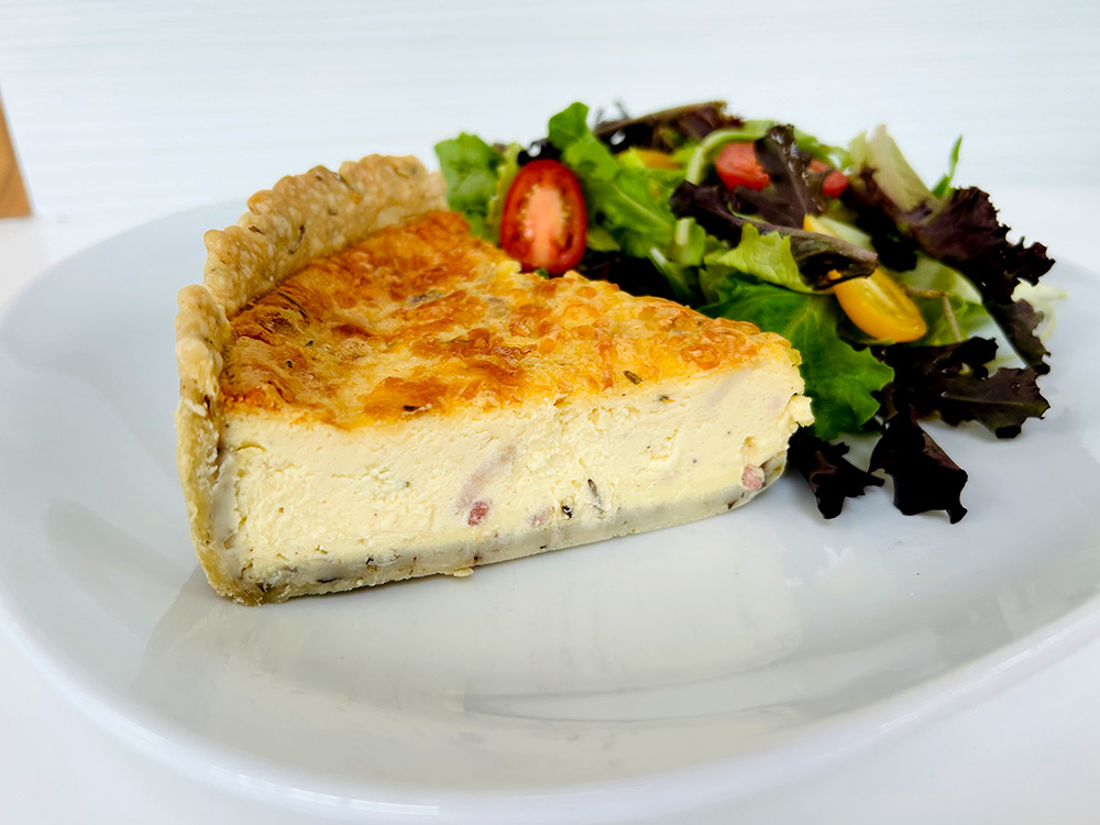 A slice of quiche lorraine and side salad by La Flamme Française